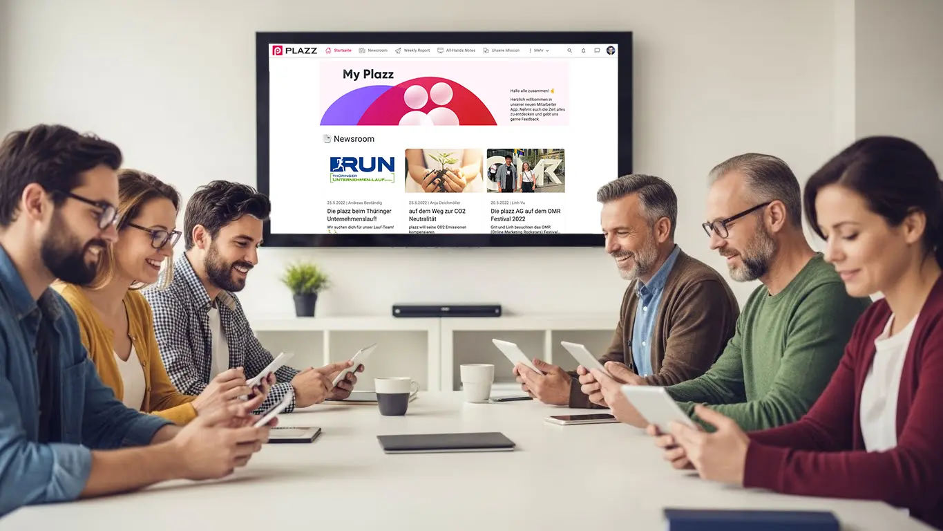 junge und ältere Verbandsmitglieder sitzen am Tisch, schauen sich ihre Verbandsapp an, im Hintergrund ist die Webversion der Verbandsapp zu sehen